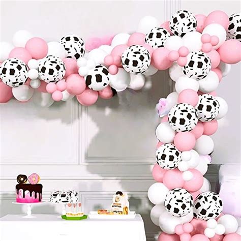 It features balloons in multiple colors and sizes, including cow print and confetti balloons, along with balloon strip and adhesive dots. . Cow balloon arch